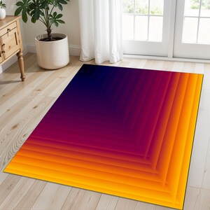 Pode incluir: Tapete geométrico abstrato com um degradê de cores laranja, amarelo, vermelho e roxo. O tapete tem um design moderno com um padrão repetitivo de quadrados.