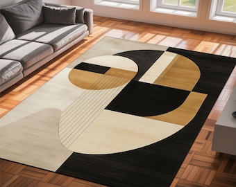 May include: Geometric patterned area rug in black, beige, and tan. The rug features a modern design with abstract shapes, including circles, rectangles, and lines. The rug is placed on a hardwood floor, with a gray sofa visible in the background.