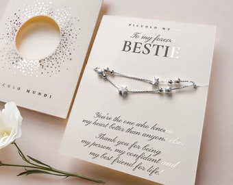 May include: A silver bracelet with star charms and small beads is displayed on a card that reads "To my forever BESTIE." The card is on a light beige background with a matching envelope. The text "PICCOLO MUNDI" is also visible.