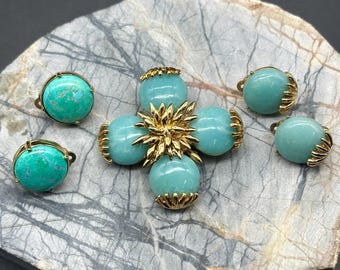 May include: A turquoise and gold tone brooch and earrings set. The brooch is a cross shape with four turquoise cabochons and a gold tone centre. The earrings are round turquoise cabochons with gold tone settings.