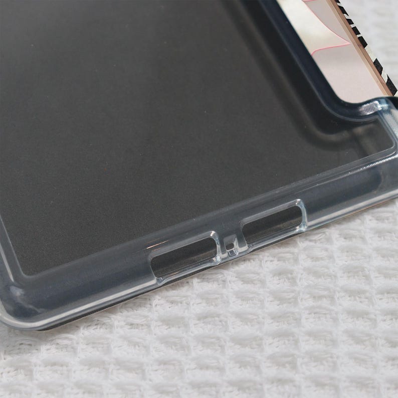 May include: A clear phone case with a black interior. The case has a transparent border and cutouts for buttons and ports. The top right corner features a design with black and white stripes and pink accents.