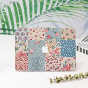 May include: A laptop skin with a patchwork design featuring various floral patterns in shades of pink, blue, and white. The skin is made up of 12 squares, each with a different floral pattern. The Apple logo is visible in the center of the skin.
