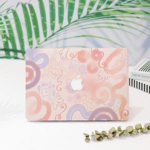May include: A pink laptop skin with a colorful abstract design featuring swirls, lines, and shapes in shades of pink, orange, and purple.