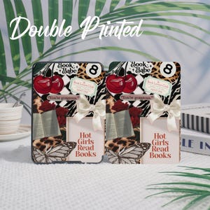 May include: Two phone cases with a collage design. Each case features cherries, a butterfly, and the text "Hot Girls Read Books." The cases have a zebra print and a bow.