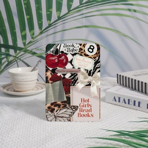 May include: A decorative rectangular card with a collage of images, including cherries, a butterfly, and leopard print. The card features the text "Book + Babe," "Hot Girls Read Books," and "You're gorgeous."