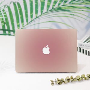 May include: A rose gold laptop computer with a white Apple logo on the lid.