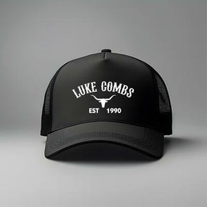 May include: Black trucker hat with a white logo that says "LUKE COMBS EST 1990" and a white bull's head graphic.