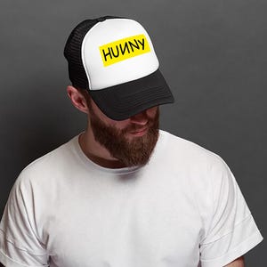 May include: A black and white trucker hat with a yellow patch that says "HUNNY" on it.