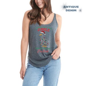 May include: A gray tank top with a Christmas goose graphic. The goose wears a Santa hat and is decorated with Christmas lights. Text on the shirt reads "Probably Just Gonna Jingle Some of the Way I'm Tired."