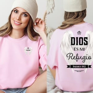 May include: Pink sweatshirt with a white angel wings design and the text "DIOS ES MI REFUGIO SALMOS 91:2".
