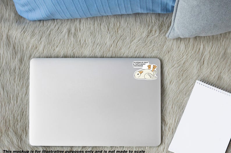 May include: A white laptop with a sticker featuring a cartoon owl lying on its back with the text "I'M DOING MY BEST & THAT'S DEEPLY CONCERNING". The laptop is on a gray, fluffy surface, with a blue pillow and a notepad.