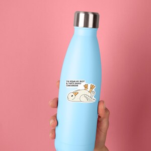May include: A light blue insulated water bottle with a silver lid. A sticker on the bottle features a cartoon duck with the text "I'M DOING MY BEST & THATS DEEPLY CONCERNING."