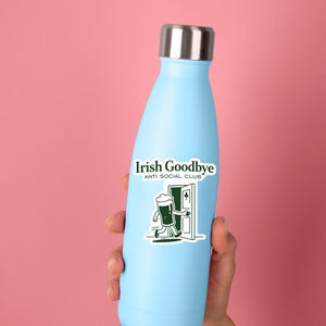 Puede incluir: Una botella de agua aislada azul claro con tapa plateada. La botella tiene una pegatina que dice "Irish Goodbye ANTI SOCIAL CLUB" con un dibujo de un vaso de cerveza saliendo por una puerta. El fondo es rosa.