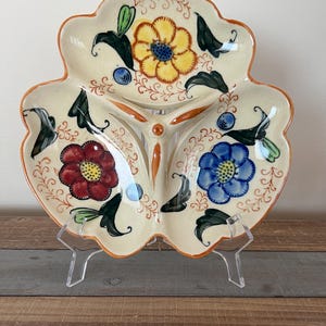 May include: A vintage ceramic serving dish with three sections. The dish is decorated with a floral pattern in shades of red, yellow, blue, and green.