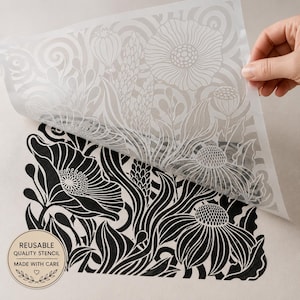 May include: A translucent plastic stencil sheet featuring a detailed botanical pattern of poppies and wildflowers. The stencil is partially lifted to reveal a crisp black ink design of the same floral motif printed on a light surface below.