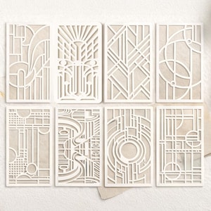 May include: Eight white Art Deco style paper cutouts with intricate geometric designs. Each cutout features a unique pattern of lines, curves, and shapes, creating a layered effect. The cutouts are arranged on a light beige background.