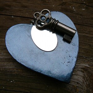 May include: A blue heart-shaped ornament with a silver mirror inside and a vintage-style key attached.