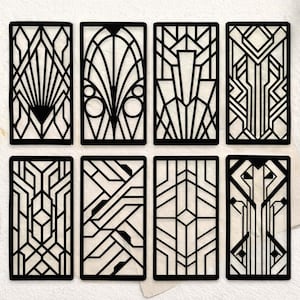 May include: Eight black Art Deco style rectangular panels with intricate geometric designs. The panels feature various symmetrical patterns, including fan-like shapes, arches, and linear arrangements. The designs are set against a neutral background.