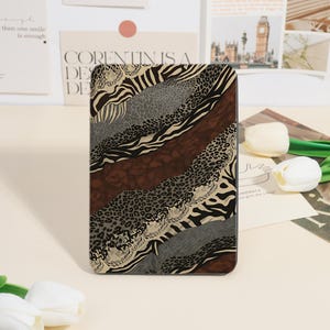 May include: A rectangular tablet case featuring a layered, diagonal collage of animal print patterns. The design incorporates black and tan zebra stripes, dark brown leopard spots, and a textured gray cheetah print, creating a bold, multi-patterned aesthetic.