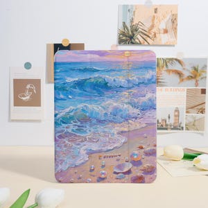 May include: A tablet case featuring a vibrant painting of a beach scene. The artwork depicts ocean waves in shades of blue and white, a sandy shore, and seashells. The case has a colorful sunset sky with a sun.