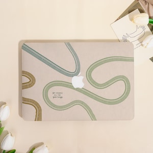 May include: A beige laptop case with a white Apple logo and abstract green and brown lines. The case has the text "you deserve all the good things" in a handwritten style font.