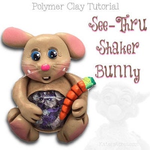 May include: A brown polymer clay bunny with pink ears and blue eyes holds a carrot in its hand. The bunny's belly is clear and filled with colorful glitter, making it a see-thru shaker bunny. The title "See-Thru Shaker Bunny" is written above the bunny.
