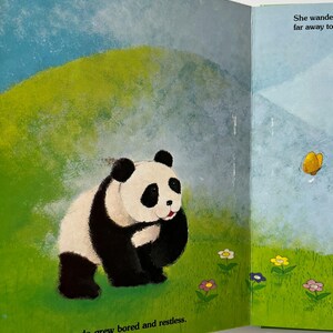 May include: A children's book illustration showing a panda bear with black and white fur on green grass. The background depicts a blue sky and a grassy hill. The text at the bottom reads, "One day, panda grew bored and restless."