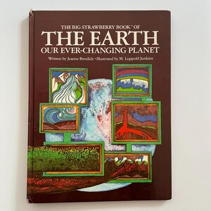 May include: A hardcover book titled The Big Strawberry Book of The Earth: Our Ever-Changing Planet, written by Jeanne Bendick and illustrated by M. Luppold Junkins. The dark brown cover features a central globe graphic with six framed illustrations depicting natural landscapes, including mountains, a volcano, and ocean waves.