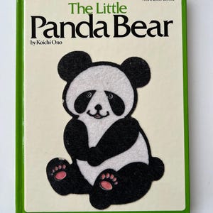 May include: A children's book titled "The Little Panda Bear" by Koichi Ono. The cover shows a felt panda bear illustration in black and white with pink paw pads. The book has a green border and the text "A Shaggy Book".