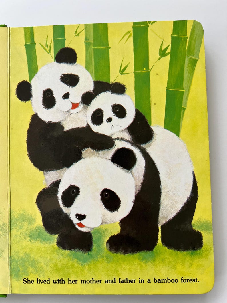 May include: A colourful children's book illustration of three pandas. The pandas are depicted in black and white with red details, set against a green background with bamboo. The text reads, "She lived with her mother and father in a bamboo forest."