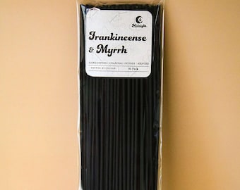May include: A package of black incense sticks. The label reads "Frankincense & Myrrh" with additional text: "Hand Dipped | Charcoal Incense | Scented". The package contains 80 sticks.