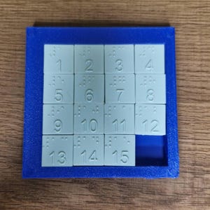 Può includere: Un puzzle con cornice blu e 15 tessere bianche numerate da 1 a 15. Le tessere sono disposte in una griglia 4x4 con una tessera mancante.