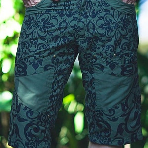 May include: Green cargo shorts with a black and white floral pattern. The shorts have multiple pockets and a belt loop.