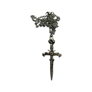 May include: A silver chain necklace with a pendant in the shape of a sword with a cross design.