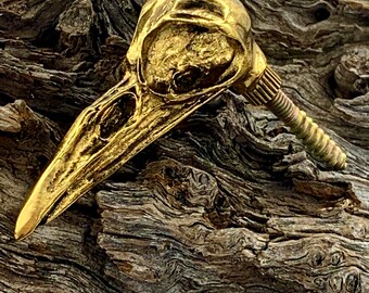 Könnte beinhalten: Ein goldfarbener Türknauf in Form eines Vogelschädels mit detailliertem Design. Der Knauf ist an einer Schraube befestigt.