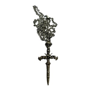 May include: A silver chain necklace with a pendant of a skull-headed sword with crossed swords on the hilt.