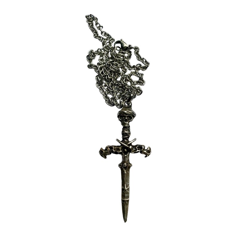 May include: A silver chain necklace with a pendant of a skull-headed sword with crossed swords on the hilt.