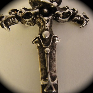 May include: A silver-toned metal sword pendant with a detailed design of three dragons on the hilt.