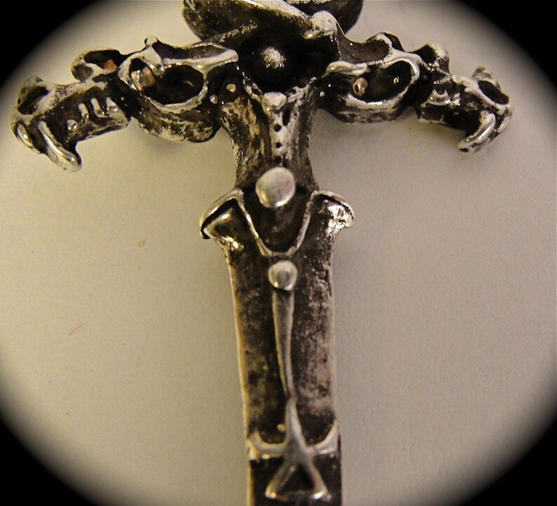 May include: A silver-toned metal sword pendant with a detailed design of three dragons on the hilt.