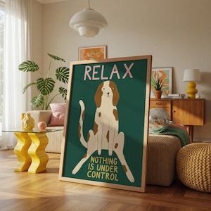 May include: A framed art print with a dog illustration and the words "RELAX" and "NOTHING IS UNDER CONTROL". The dog is white with brown markings, set against a dark green background. The frame is wooden. The print is displayed in a living room.