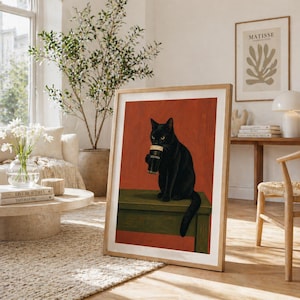 Puede incluir: Impresi&oacute;n enmarcada de un gato negro sosteniendo una pinta de Guinness. El gato est&aacute; sentado sobre una superficie verde contra un fondo rojo. La impresi&oacute;n est&aacute; en un marco de madera en una habitaci&oacute;n luminosa.