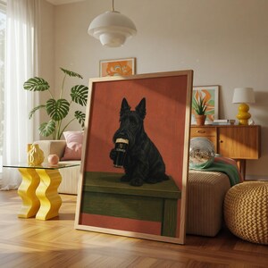 May include: A framed print featuring a black Scottish Terrier dog holding a pint of Guinness. The dog is sitting on a green surface against a red background. The print is displayed in a bright, modern living room setting.