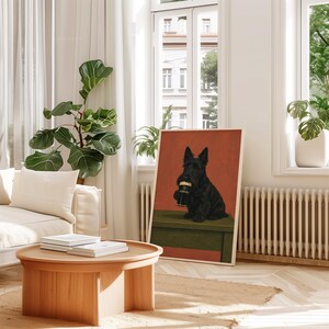 May include: A framed art print featuring a black Scottish Terrier holding a pint of Guinness. The artwork is set against a red background and a green surface. The print is displayed in a bright, airy room with a wooden coffee table and a white sofa.