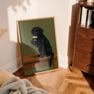 Pu&ograve; includere: Stampa incorniciata con un Labrador Retriever nero che tiene in mano una pinta di Guinness. Il cane &egrave; seduto su una panca di legno su uno sfondo verde. La stampa &egrave; esposta in una stanza con mobili in legno e pavimento a motivi.