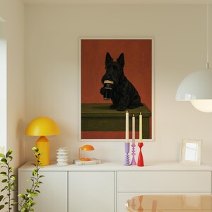 May include: A framed art print featuring a black Scottish Terrier dog holding a pint of Guinness. The dog is set against a red background, with a green table. The print is displayed above a white cabinet.