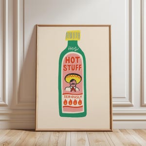Puede incluir: Una impresión enmarcada con una ilustración caprichosa de una botella de salsa picante. La botella verde tiene una tapa amarilla y una etiqueta rosa que dice "HOT STUFF" con un personaje de dibujos animados con un sombrero. La frase "SERIOUSLY" y llamas están en la parte inferior.