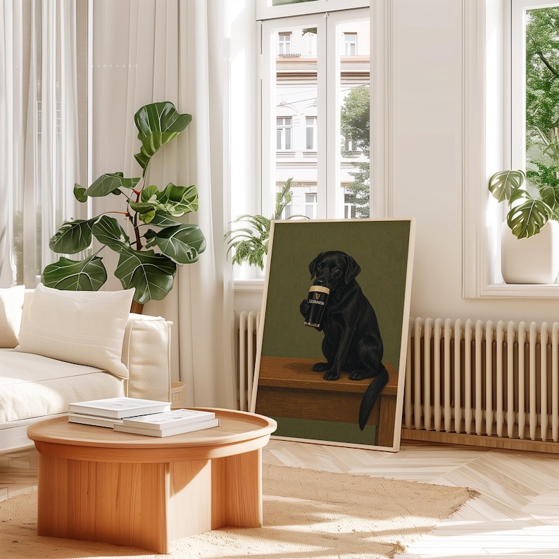 Pu&ograve; includere: Una stampa artistica incorniciata con un Labrador Retriever nero che tiene in mano una pinta di Guinness. Il cane &egrave; seduto su una superficie di legno contro uno sfondo verde. La stampa &egrave; esposta in una stanza luminosa con un tavolino di legno e una grande pianta in vaso.