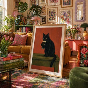Puede incluir: Un cuadro enmarcado con un gato negro sosteniendo una pinta de Guinness. El gato est&aacute; sentado sobre una superficie verde contra un fondo rojo-naranja. La impresi&oacute;n est&aacute; en un marco de madera, creando un ambiente c&aacute;lido.