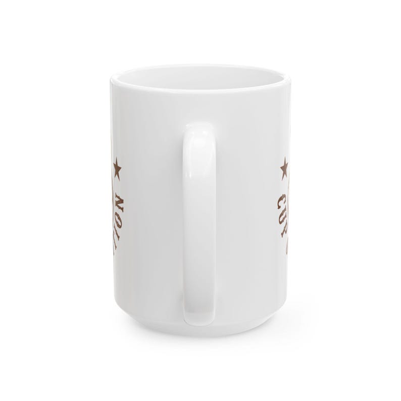 Puede incluir: Una taza de cer&aacute;mica blanca con un asa vertical, que presenta texto marr&oacute;n y un gr&aacute;fico de estrella en el lateral. El texto visible incluye la palabra CUP y una parte de una palabra que termina en TION, impresa en una fuente serif desgastada.