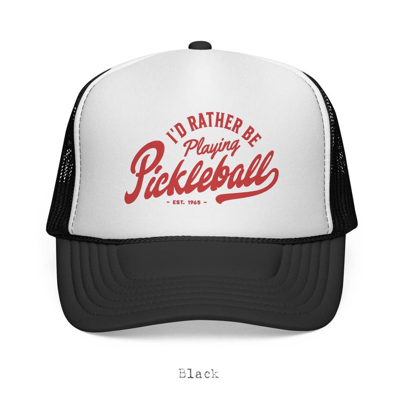 Puede incluir: Gorra de camionero en blanco y negro con el texto rojo "I'D RATHER BE Playing Pickleball - EST. 1965". La gorra tiene una visera negra y una parte trasera de malla, con un panel frontal blanco.